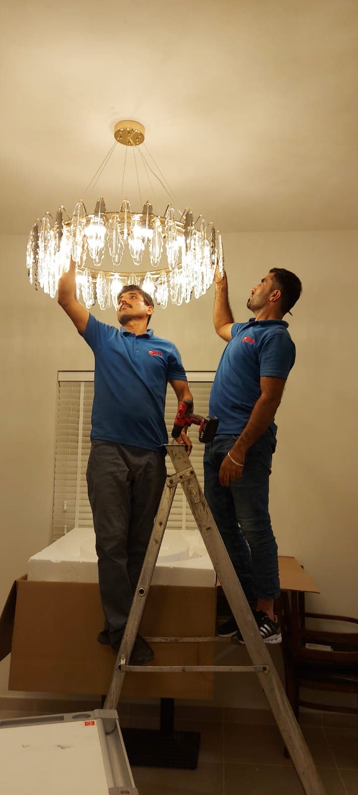 ARZ Movers handymen installing a luxury crystal chandelier in a Dubai residence