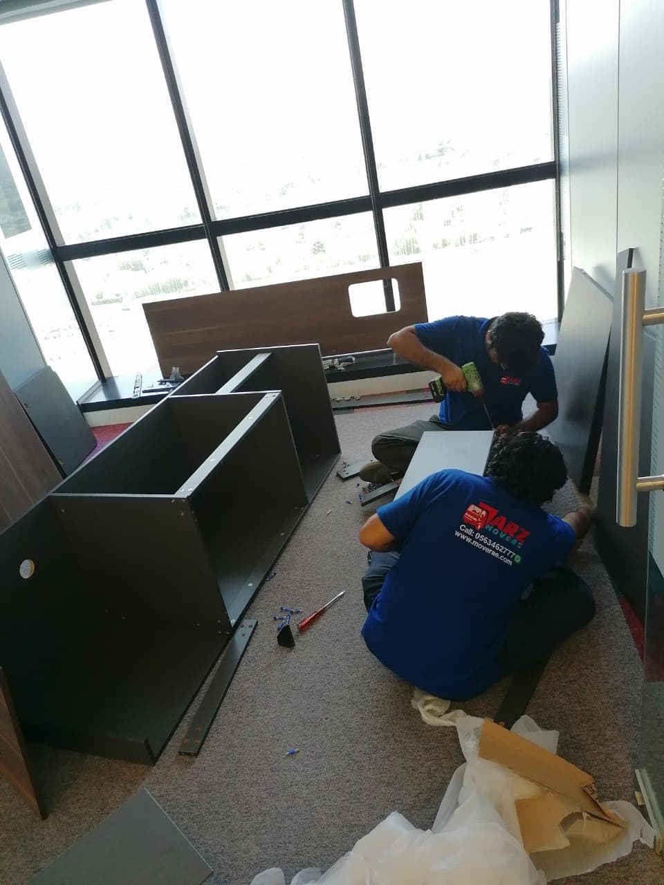ARZ Movers crew assembling modular office workstations in a Dubai high-rise