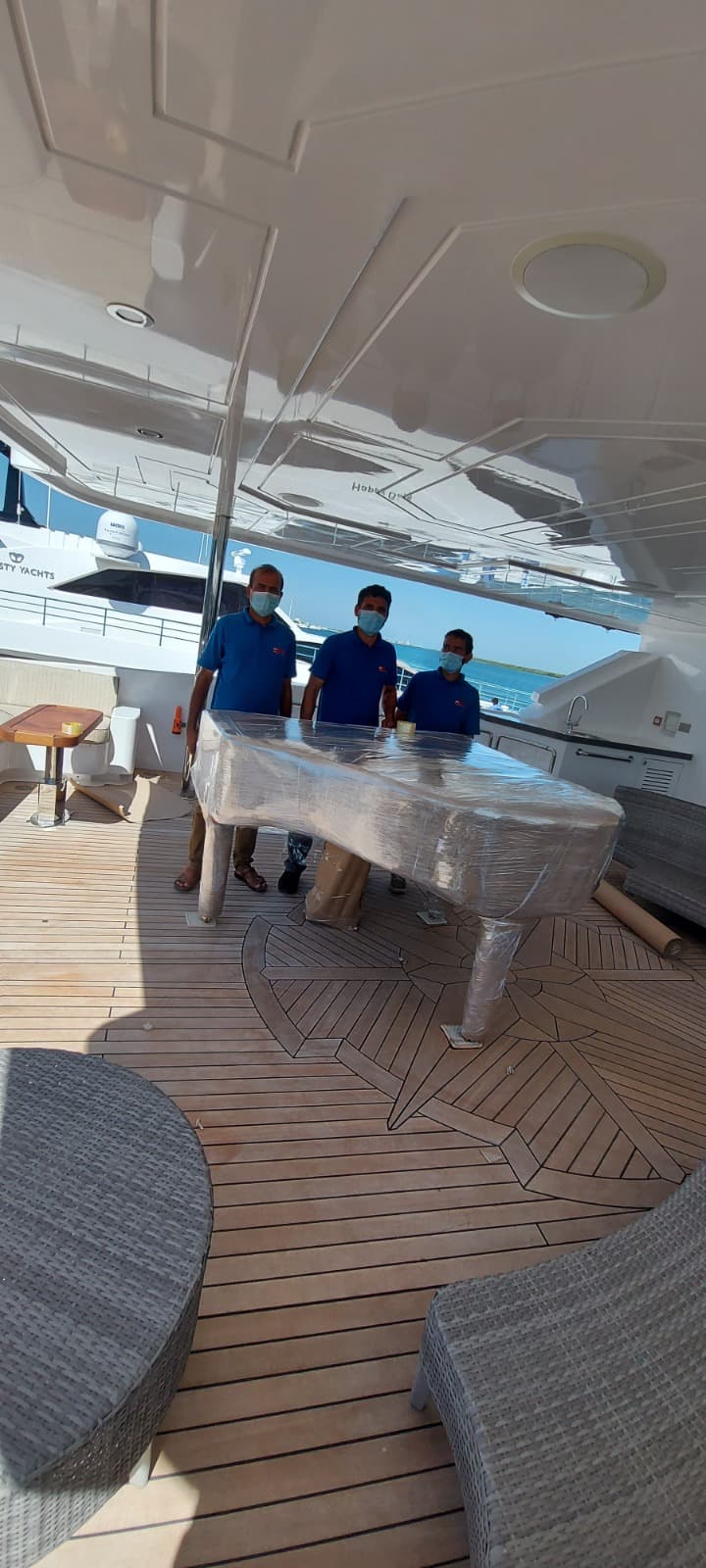 ARZ Movers crew handling a wrapped grand piano on a luxury yacht in Dubai