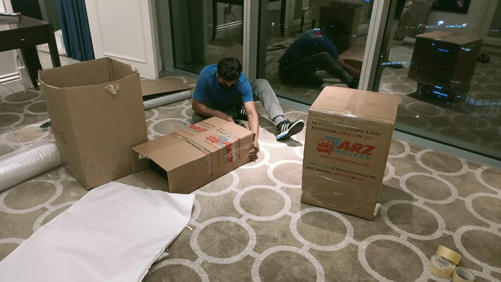 ARZ Movers packer assembling and taping branded boxes inside a Dubai apartment