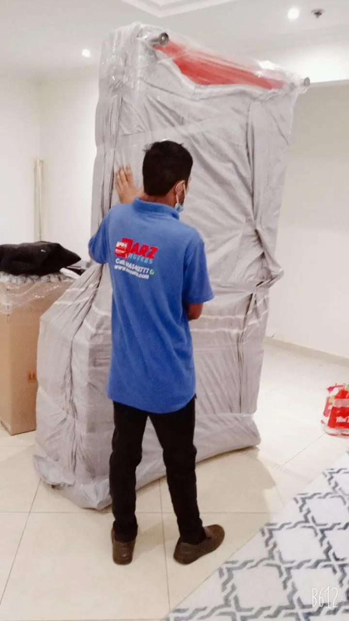 ARZ Movers packer wrapping a tall wardrobe in protective material